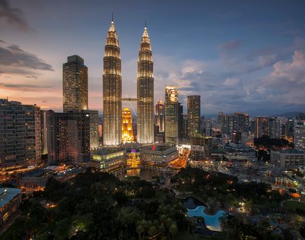 erleuchtete petronas towers mit skyline von kuala lumpur bei nacht